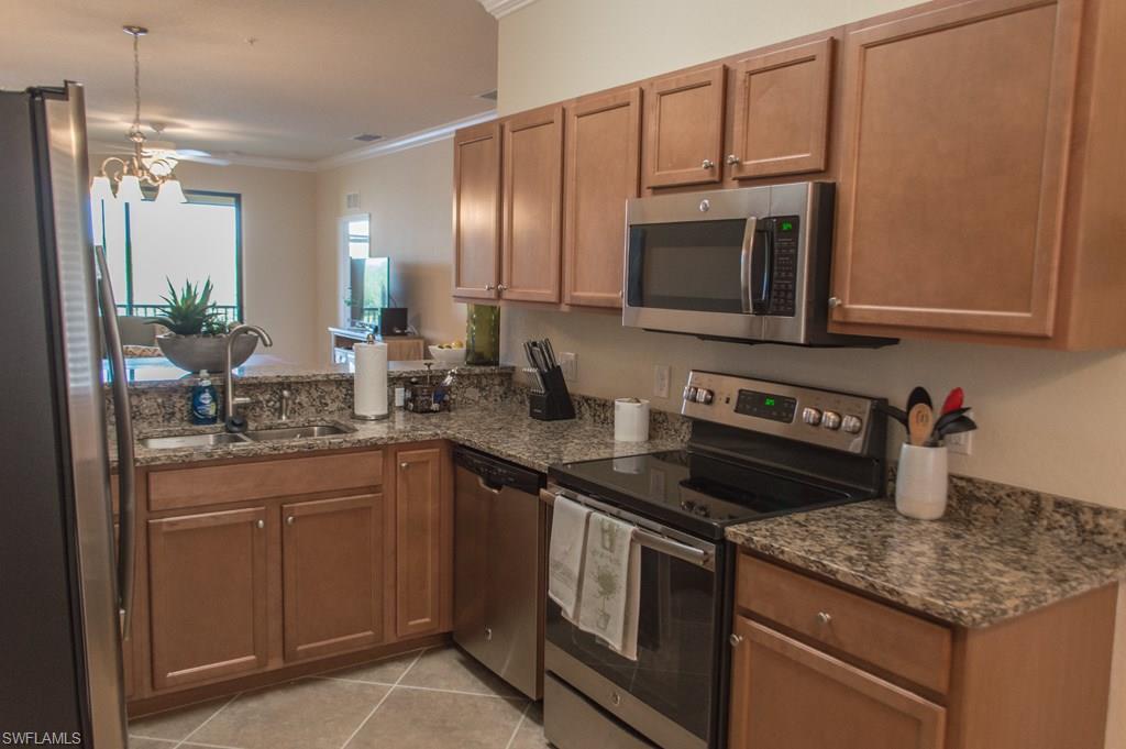 9566 Trevi Court, Unit 4943 Naples, FL 34113 - Photo 15 of 47 a kitchen with stainless steel appliances granite countertop a sink stove and microwave