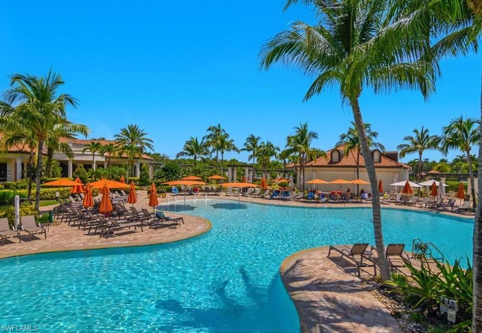 9566 Trevi Court, Unit 4943 Naples, FL 34113 - Photo 31 of 47 a view of a swimming pool with a table and chairs potted plants and palm trees