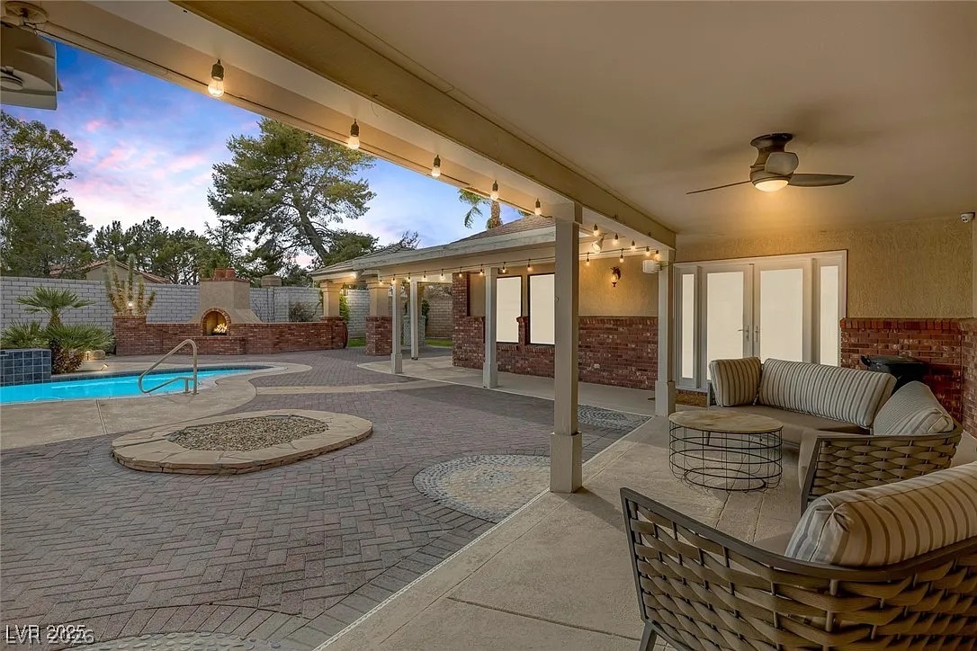 9 Quail Run Road Henderson, NV 89014 - Photo 39 of 57 An inviting outdoor living space features a sparkling pool and a charming brick fireplace under a covered patio.