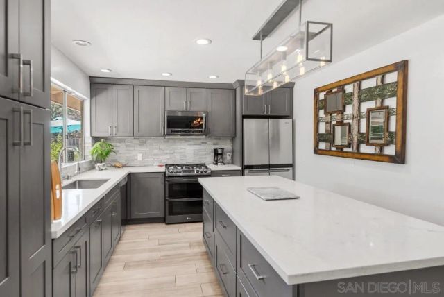a kitchen with kitchen island granite countertop a stove top oven a sink a counter top space and cabinets
