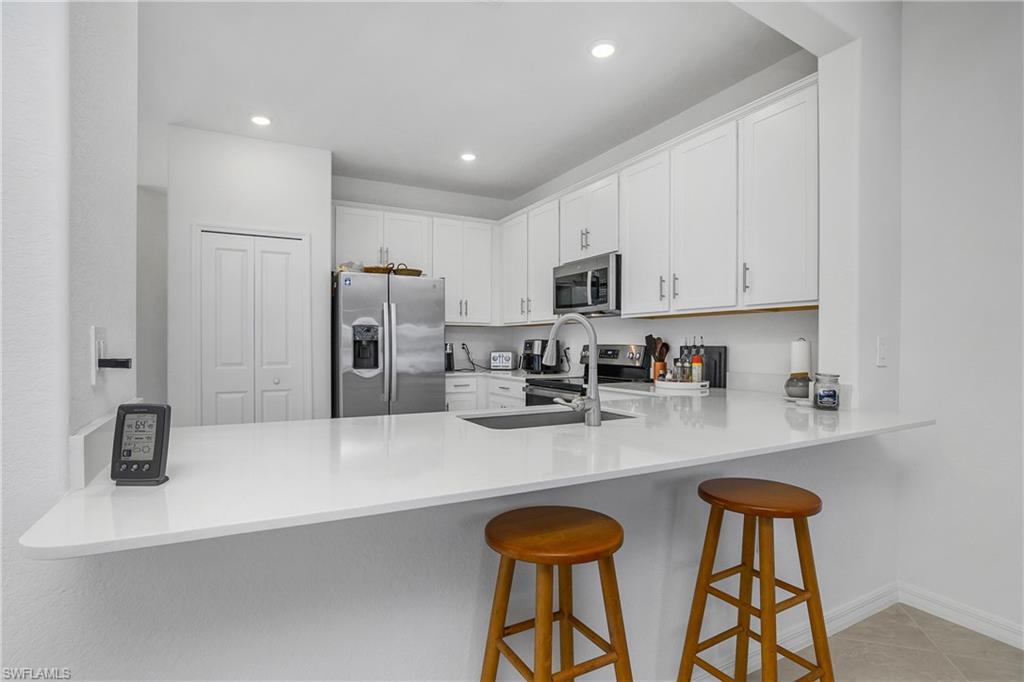 2215 Dragonfruit Way Naples, FL 34120 - Photo 11 of 30 a kitchen with stainless steel appliances granite countertop a sink a stove and cabinets