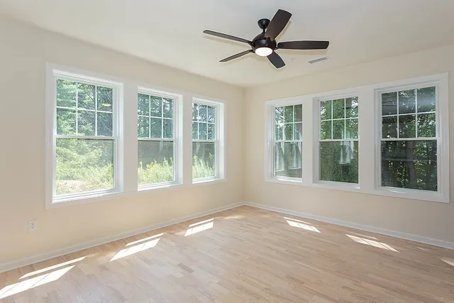 a view of an empty room with wooden floor and a window