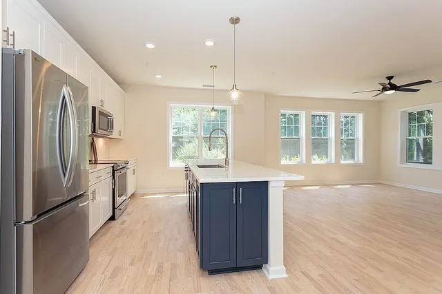 a kitchen with stainless steel appliances granite countertop a refrigerator a sink a stove and a wooden floors