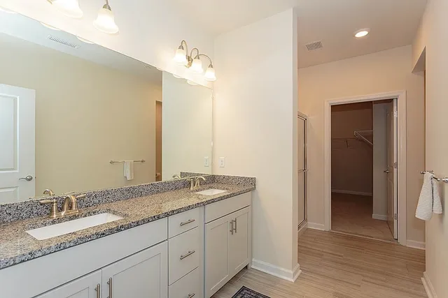 a bathroom with a granite countertop double vanity sink and a mirror