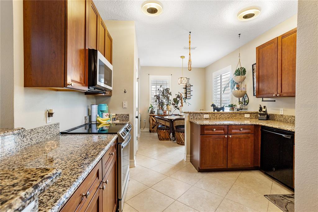 6911 Beargrass Road Harmony, FL 34773 - Photo 13 of 60 a kitchen with stainless steel appliances granite countertop a sink counter space cabinets and a large window
