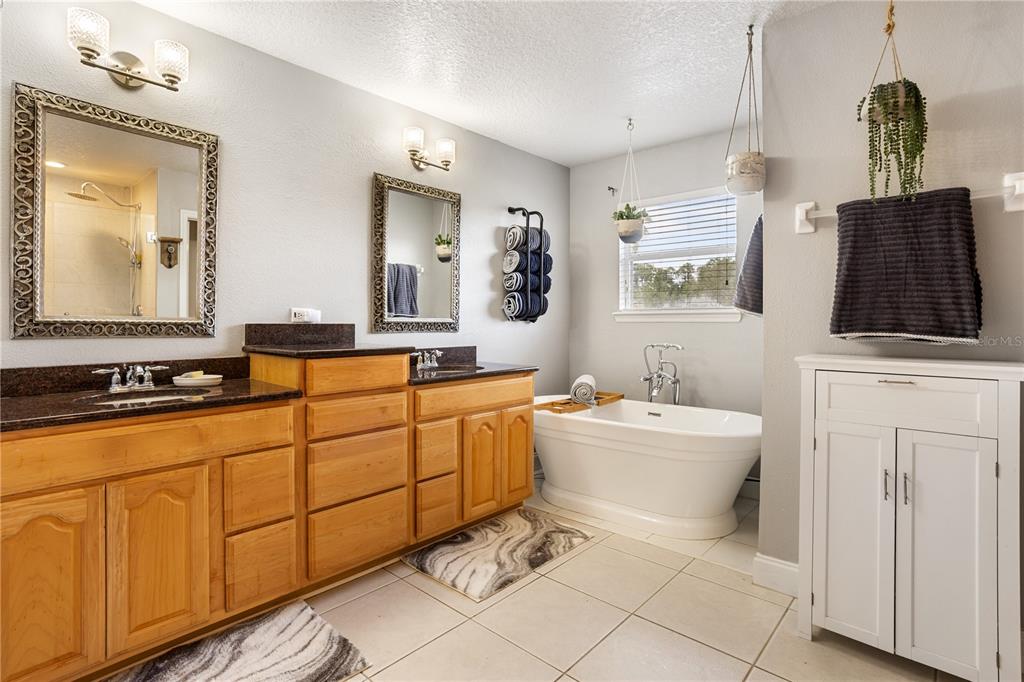 6911 Beargrass Road Harmony, FL 34773 - Photo 22 of 60 a bathroom with a sink a mirror a bathtub and a window