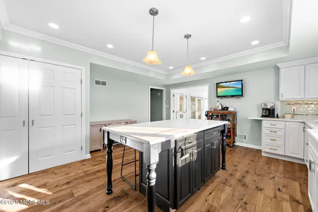 a large kitchen with kitchen island a stove a chimney a sink dishwasher and wooden cabinets with wooden floor