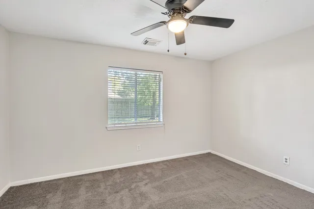 an empty room with a window and a fan