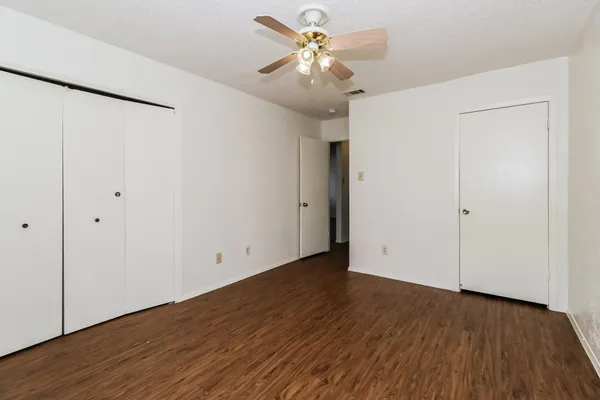 an empty room with wooden floor and a ceiling fan