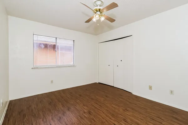 an empty room with wooden floor and a ceiling fan