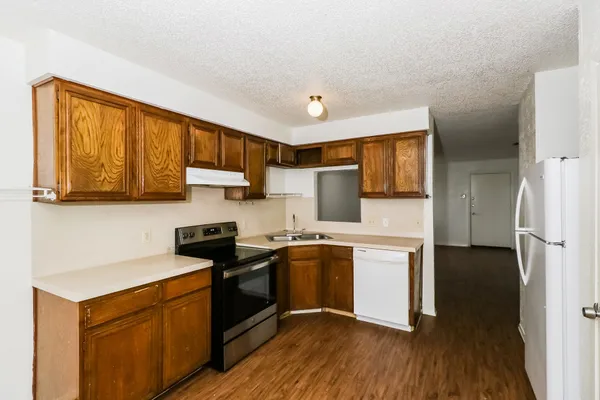 a kitchen with stainless steel appliances granite countertop a refrigerator stove top oven a sink and dishwasher with wooden floor