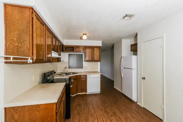 a kitchen with a refrigerator a stove top oven a sink and cabinets