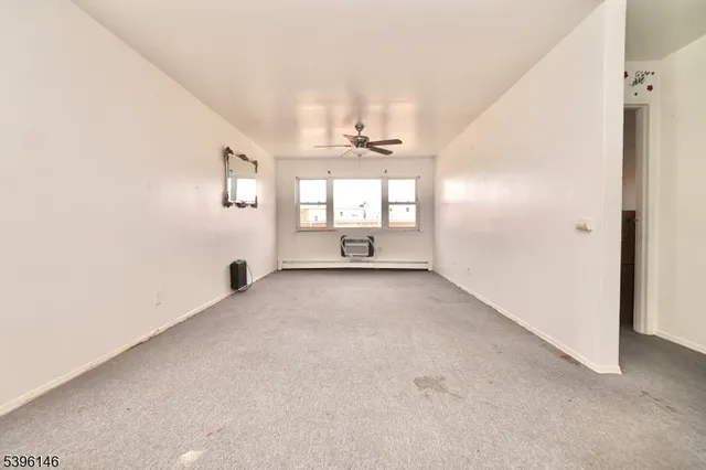 an empty room with windows and ceiling fan