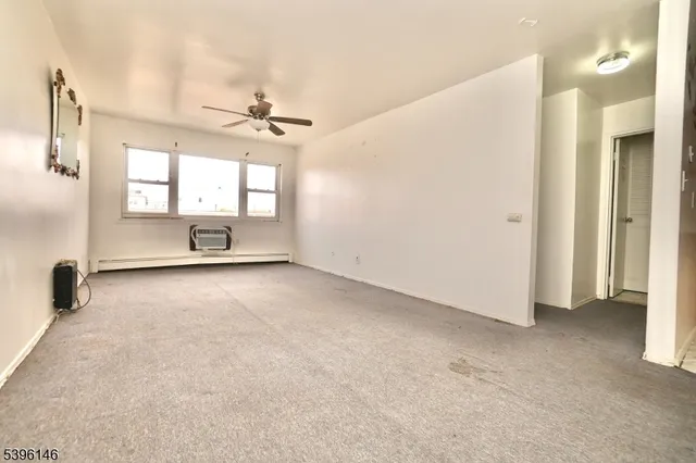 an empty room with windows and ceiling fan