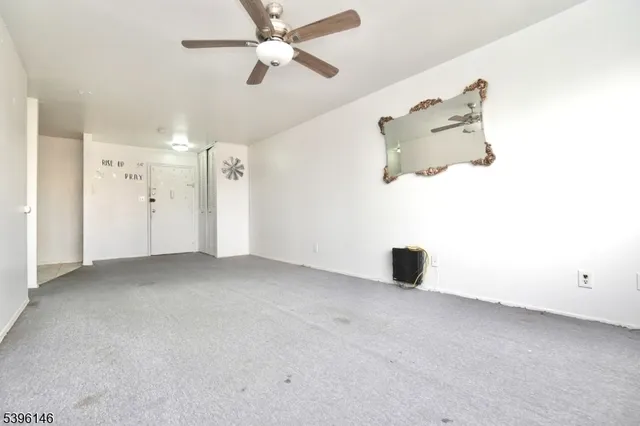 an empty room with ceiling fan and window