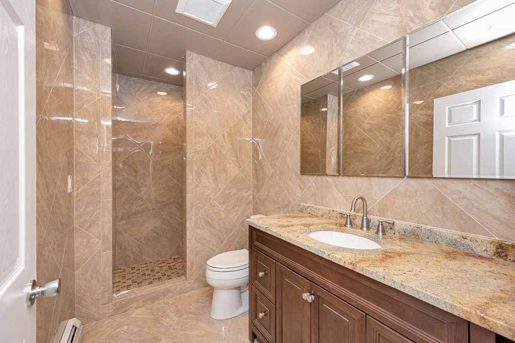 23 Lane Road Pelham, NH 03076 - Photo 30 of 42 a bathroom with a granite countertop sink a toilet and shower