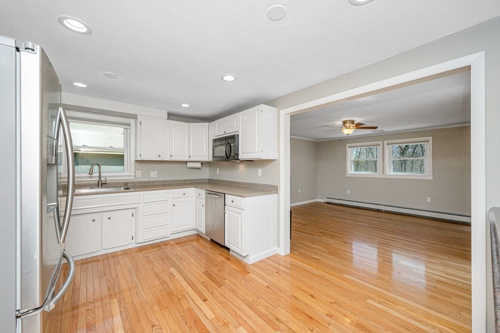 23 Lane Road Pelham, NH 03076 - Photo 6 of 42 a kitchen with granite countertop a stove and white cabinets with wooden floor