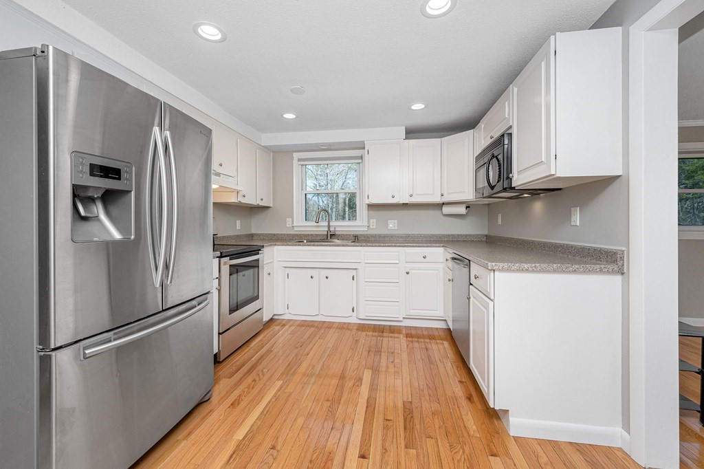 23 Lane Road Pelham, NH 03076 - Photo 7 of 42 a kitchen with white cabinets stainless steel appliances and a refrigerator