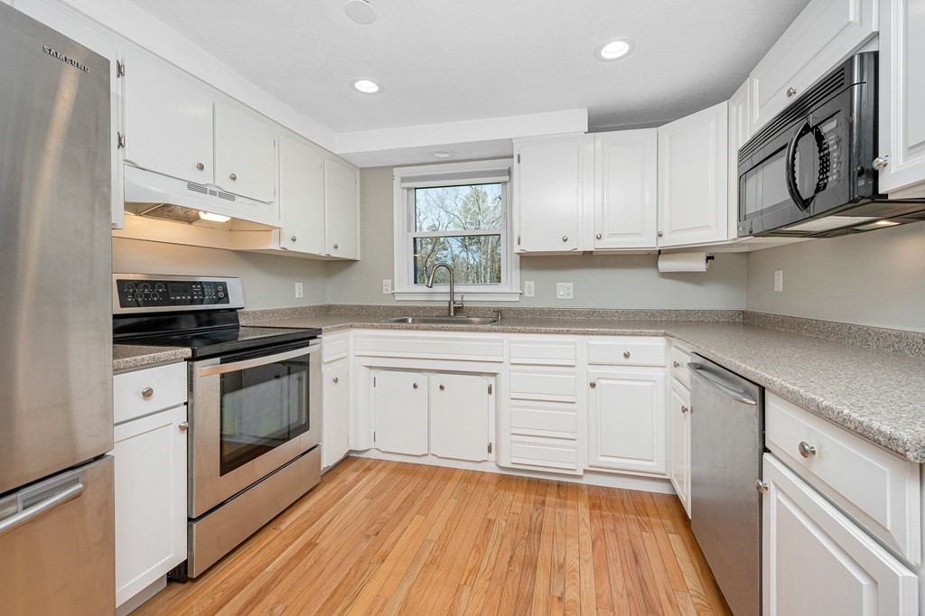 23 Lane Road Pelham, NH 03076 - Photo 8 of 42 a kitchen with granite countertop white cabinets white appliances and sink