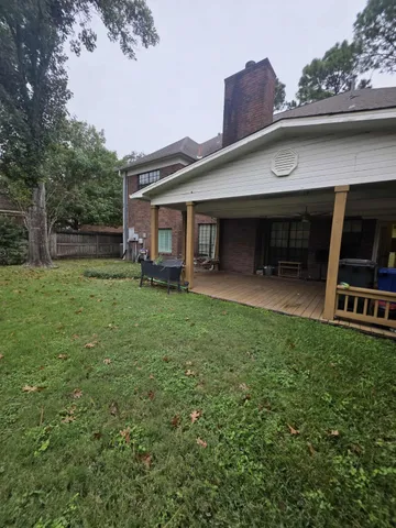 a view of a wooden deck with a table and chairs next to a yard