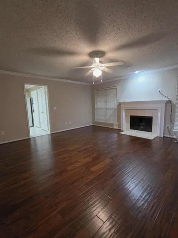 a view of an empty room with wooden floor fireplace and a window