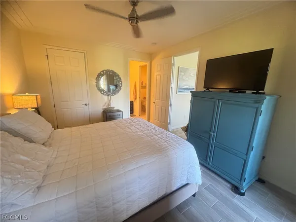 a bedroom with a flat screen tv on dresser and a window