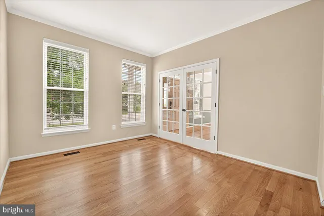 an empty room with wooden floor and ceiling fan