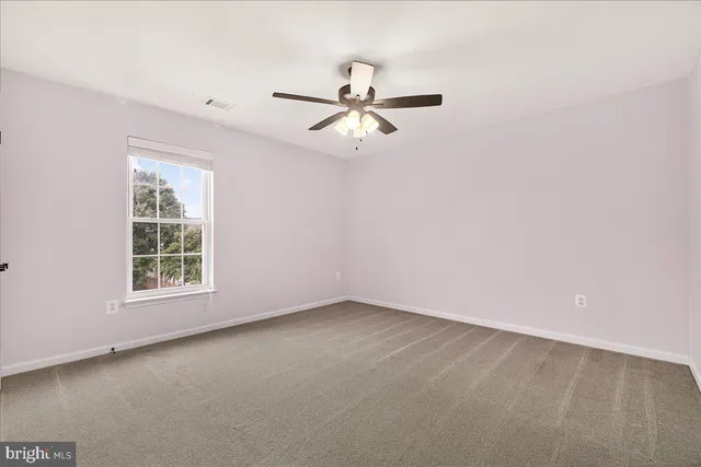 an empty room with chandelier fan and closet area