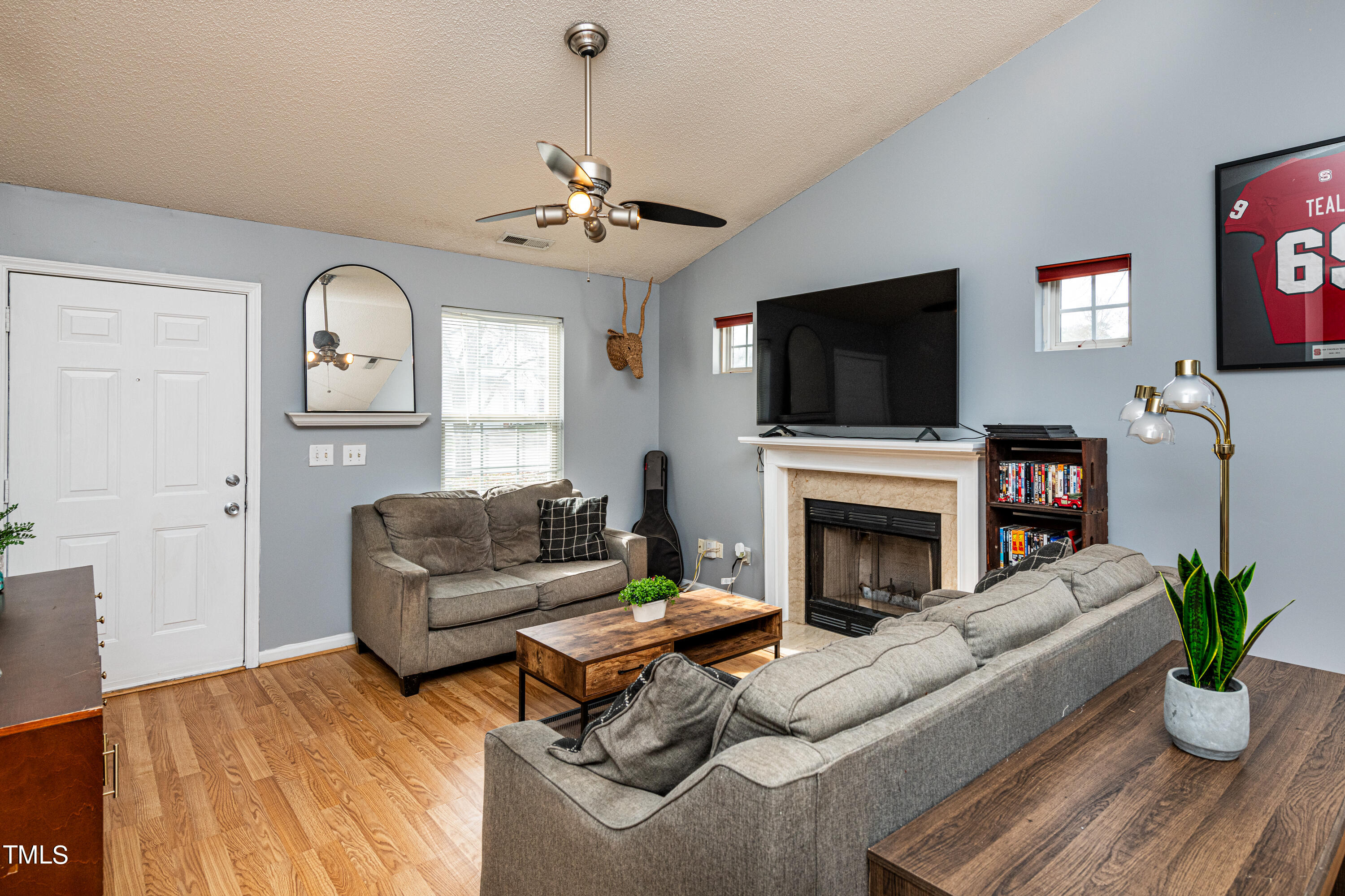 4225 Lake Woodard Drive Raleigh, NC 27604 - Photo 9 of 27 a living room with furniture a fireplace and a flat screen tv