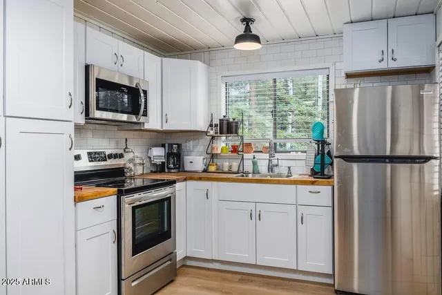 a kitchen with stainless steel appliances granite countertop a refrigerator a stove a sink and a microwave