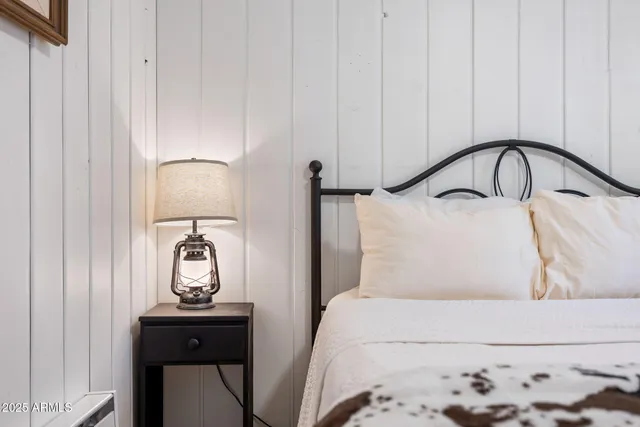 a bedroom with a bed and a potted plant on the dresser