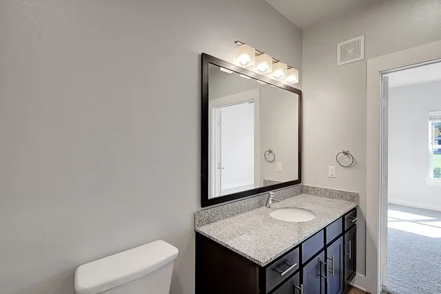a bathroom with a granite countertop sink and a mirror