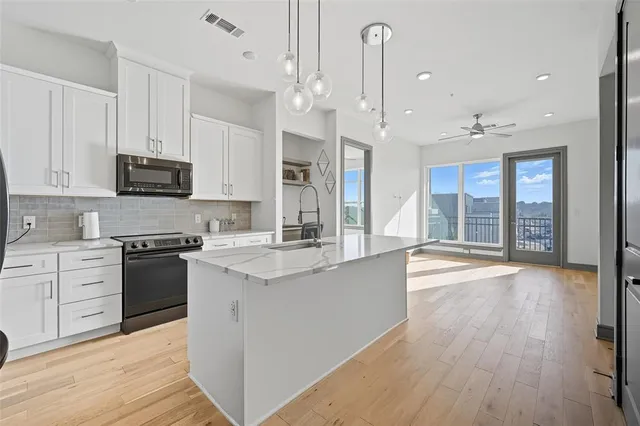 a large kitchen with stainless steel appliances granite countertop a stove and a wooden floors