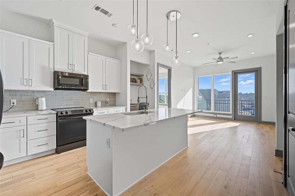2700 Old Denton Road, Unit 3310 Carrollton, TX 75007 - Photo 2 of 21 a large kitchen with stainless steel appliances granite countertop a stove and a wooden floors