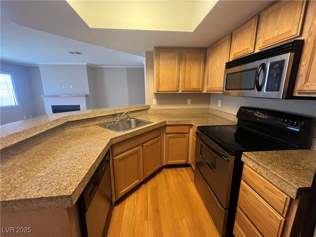 8600 West Charleston Boulevard, Unit 1060 Las Vegas, NV 89117 - Photo 6 of 14 Kitchen with appliances with stainless steel finishes, light wood-style flooring, a peninsula, light countertops, and a fireplace