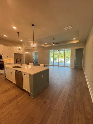 a large kitchen with stainless steel appliances a large counter top a sink a refrigerator and a wooden floor