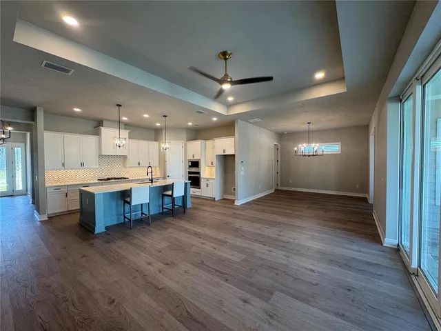 a open kitchen with stainless steel appliances granite countertop a large counter top a stove and a wooden floors