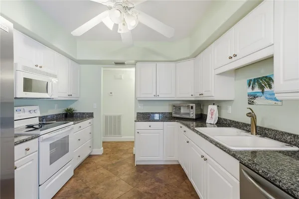 a kitchen with granite countertop a sink stainless steel appliances and white cabinets