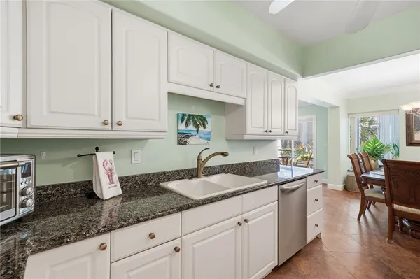 a kitchen with granite countertop a sink white cabinets and stainless steel appliances