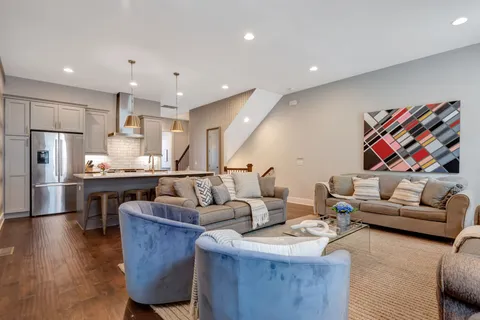 a living room with furniture kitchen view and a wooden floor