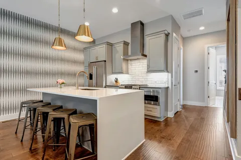 a kitchen with kitchen island granite countertop a sink cabinets and wooden floor