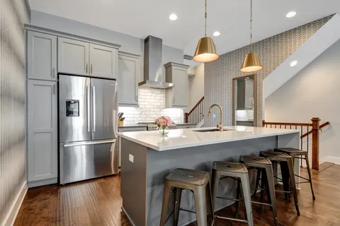 a kitchen with stainless steel appliances a refrigerator a sink and wooden floors