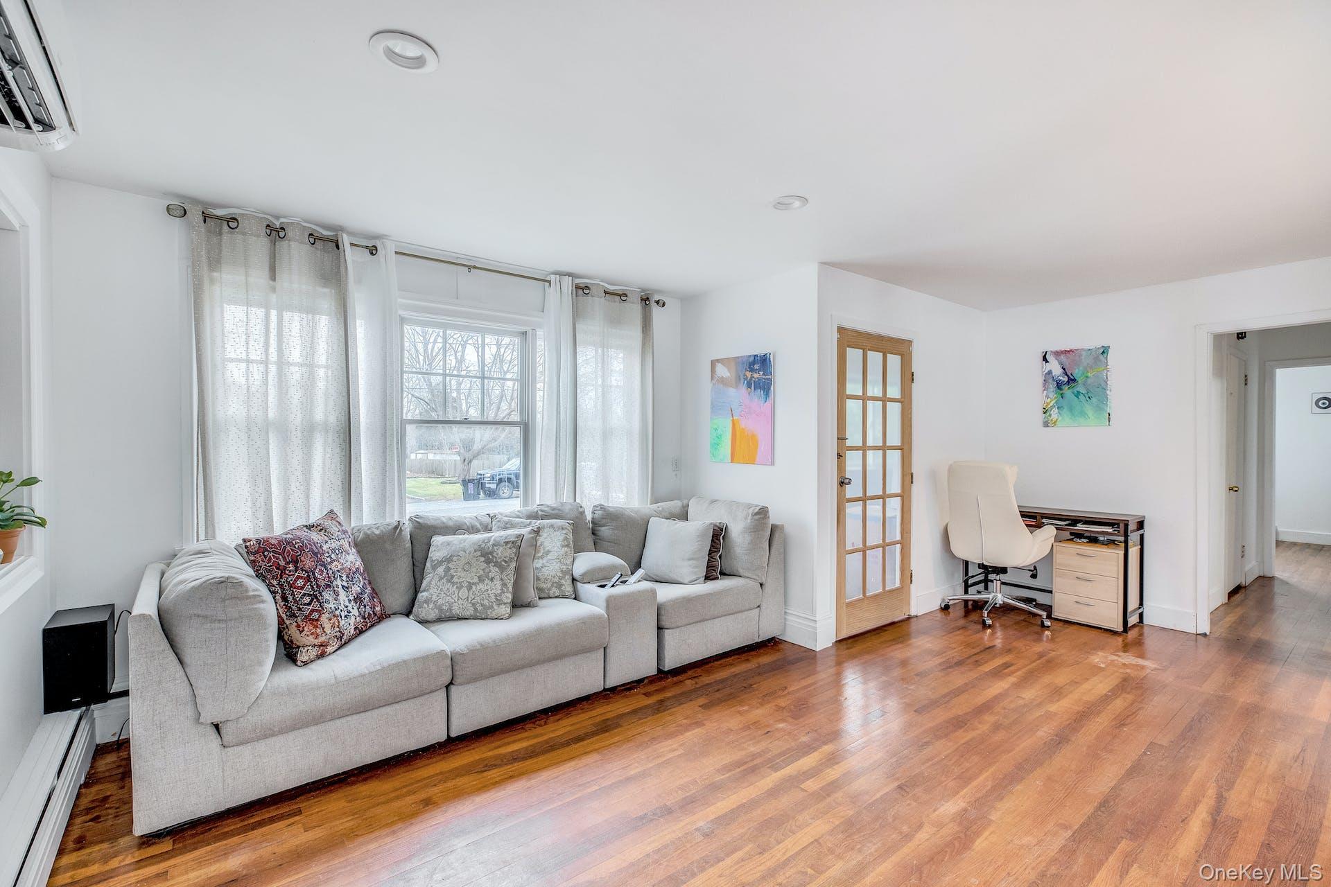 7 George Street Hampton Bays, NY 11946 - Photo 4 of 11 Spacious living area featuring rich hardwood flooring, crisp white walls, recessed ceiling lighting, and large windows with privacy treatments