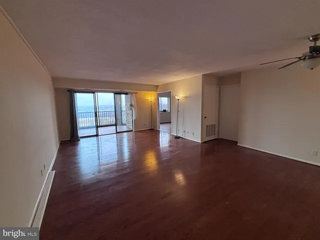 a view of an empty room with wooden floor and a window