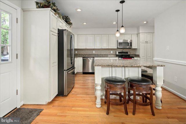 a kitchen with kitchen island a dining table chairs stainless steel appliances and cabinets