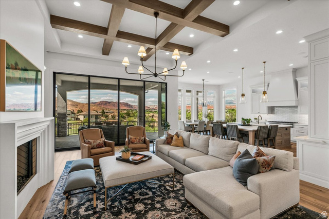 2608 Canyon Ridge Drive St. George, UT 84770 - Photo 9 of 86 Spacious living area featuring exposed wood-finish ceiling beams, expansive black-framed glass sliding doors, and a white mantel fireplace