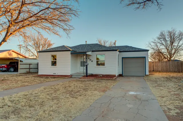 a view of a house with a yard and large tree
