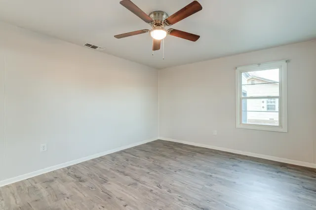 an empty room with a window and a fan