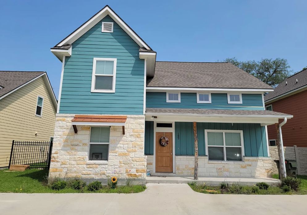 View of front of home with stone siding, fence, co