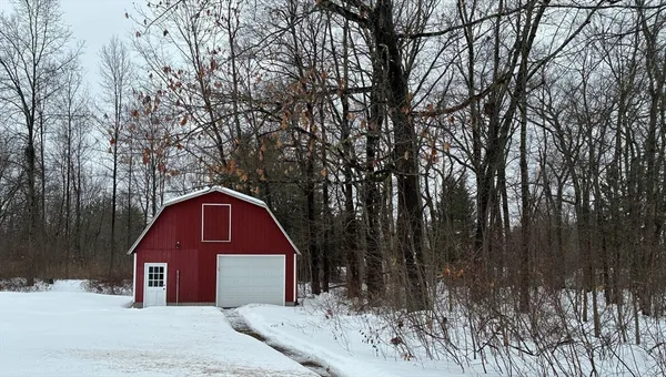 a view of a wooden house with a yard covered with snow